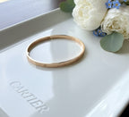 Gold bracelet on a Cartier box with flowers in the background