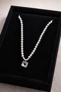 Pearl necklace with a silver clasp on a black display box.