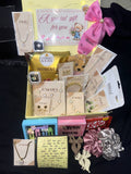 Gift basket with various items including chocolates, jewelry boxes, and decorative bows on a dark background.