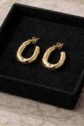 Gold hoop earrings on a black velvet display box.