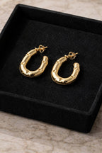 Gold hoop earrings on a black velvet display box.