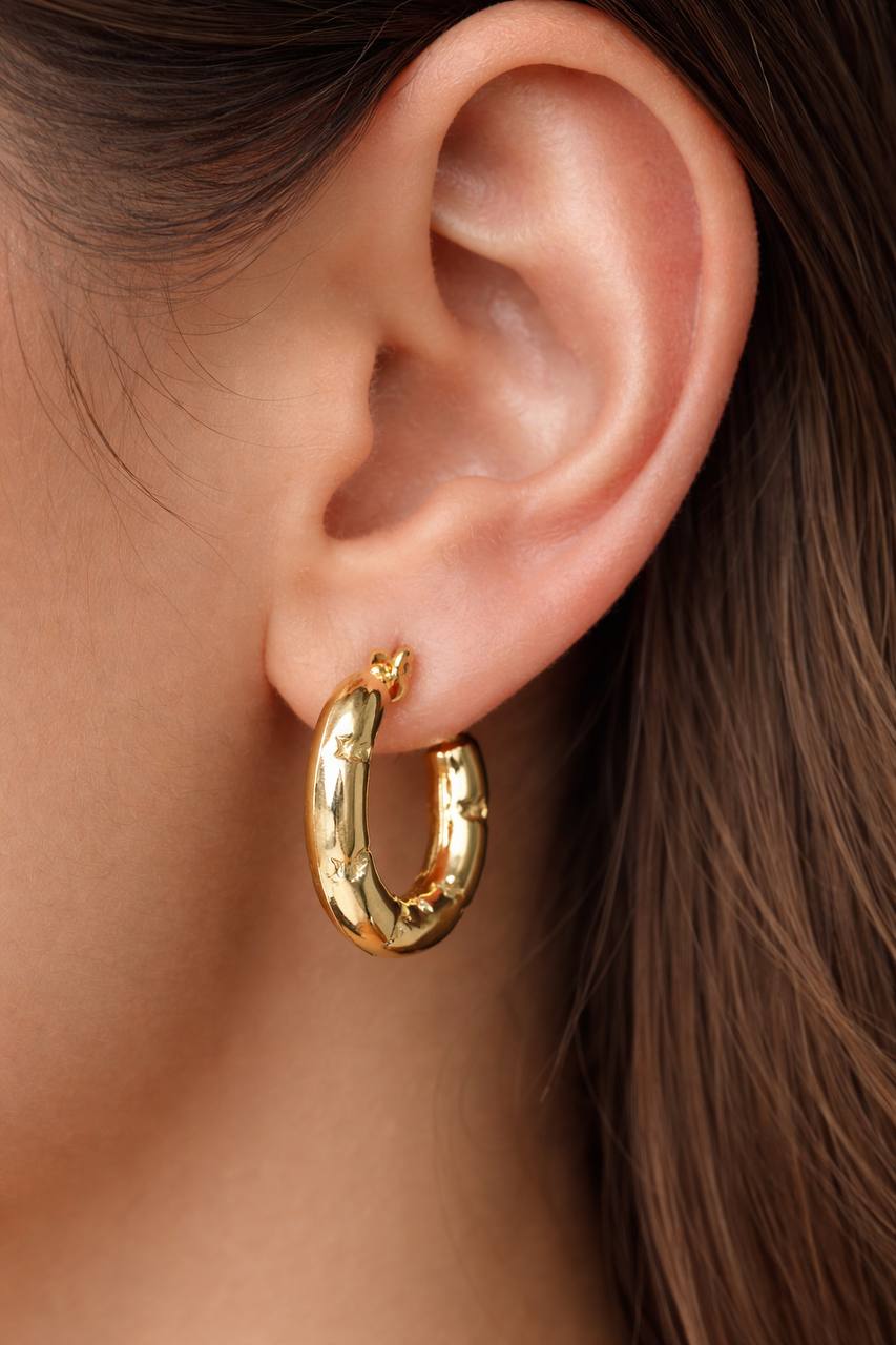 Gold hoop earring worn by a person with brown hair.
