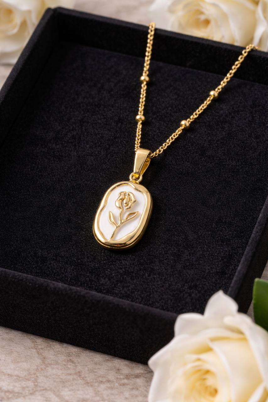 Gold necklace with a rose pendant on a black box with white roses in the background