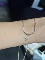 Gold necklace with a star pendant on a wrist against a blurred background