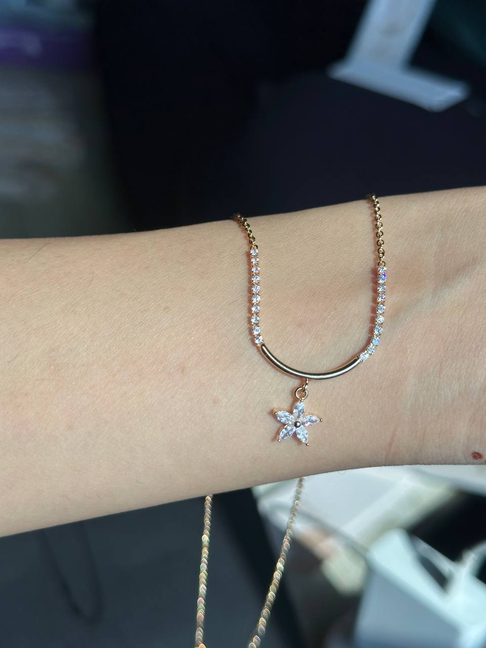 Gold necklace with a star pendant on a wrist against a blurred background