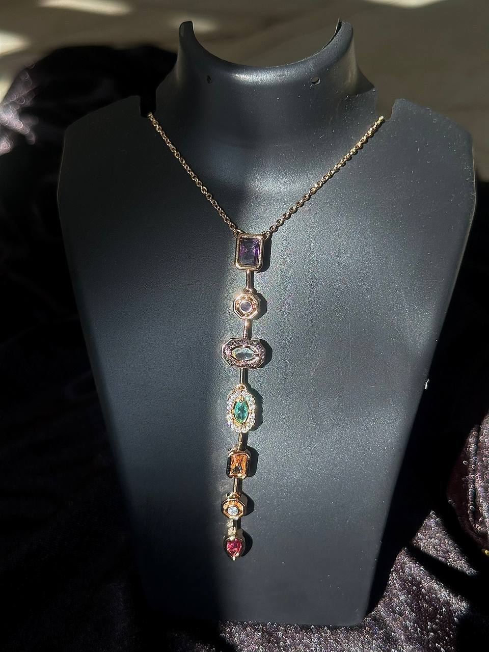 Necklace with colorful gemstones on a black mannequin bust