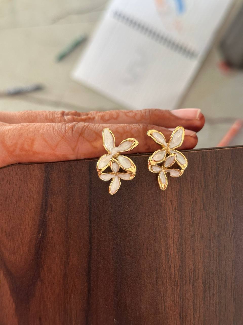 Gold butterfly earrings on a wooden surface with a blurred background