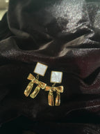 Gold earrings with bow design on a black fabric background