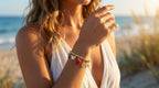 Woman on a beach wearing a white dress and multiple bracelets.