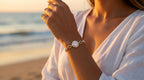 Person wearing a gold bracelet with a diamond on a beach at sunset