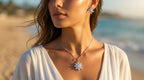 Woman wearing a silver necklace and earrings with a blurred beach background