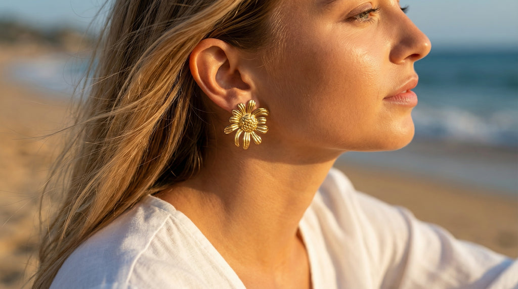 Woman wearing gold flower earrings on a beach