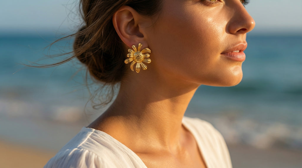Woman wearing gold earrings with a blurred beach background