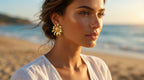 Woman wearing gold earrings on a beach with ocean in the background
