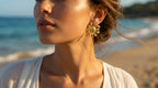 Woman wearing gold earrings with a beach background