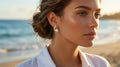 Woman wearing pearl earrings with a beach background