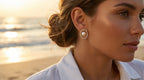 Woman wearing pearl earrings with a beach sunset in the background