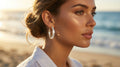 Woman wearing hoop earrings on a beach with ocean in the background