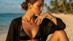 Woman in black bikini and cover-up sitting on a beach with palm trees in the background