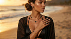 Woman on a beach wearing black jewelry with a sunset background