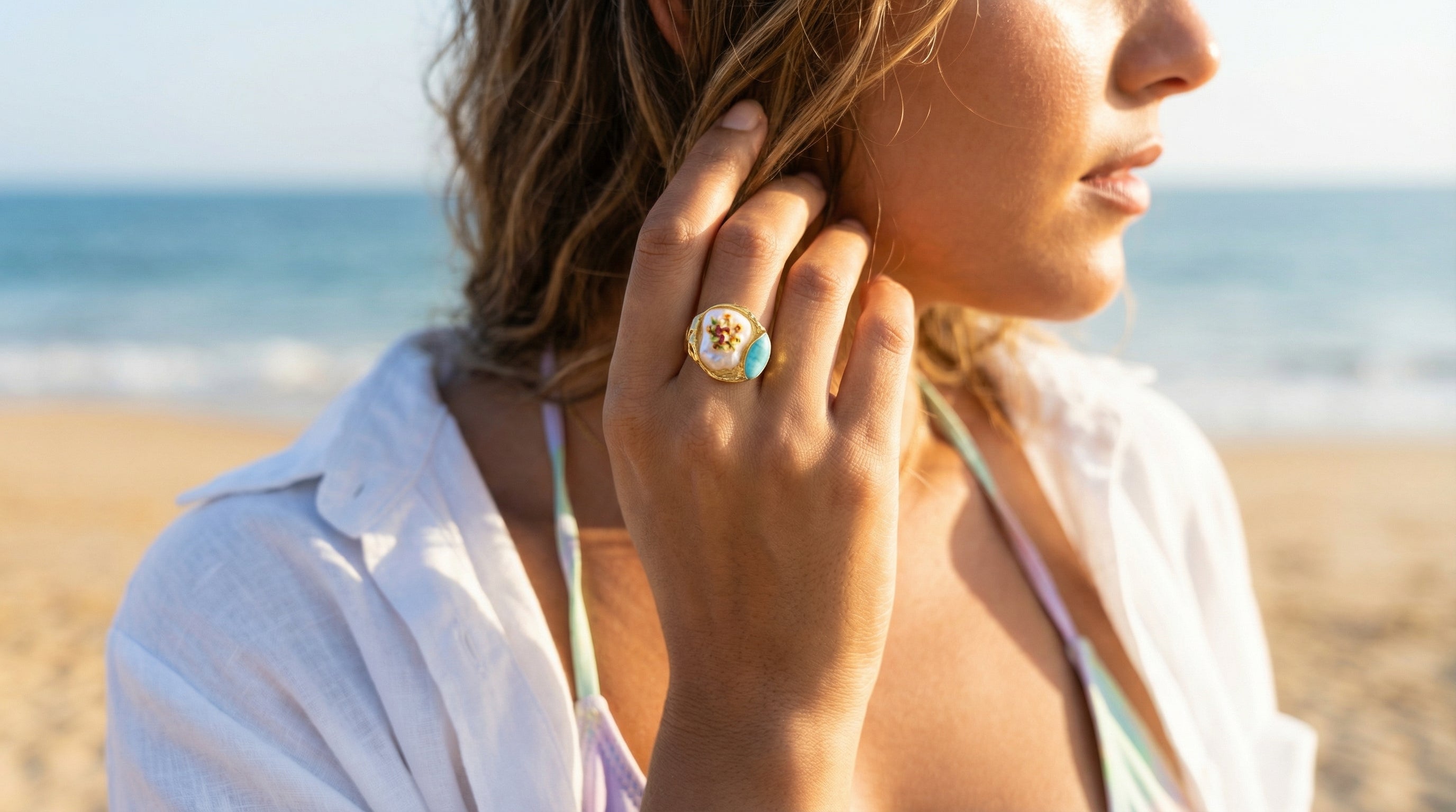 Woman on a beach wearing a ring with a blue gemstone
