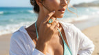 Woman on a beach wearing a turquoise ring and white shirt with ocean in the background
