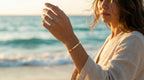 Woman on a beach wearing a gold bracelet with ocean in the background