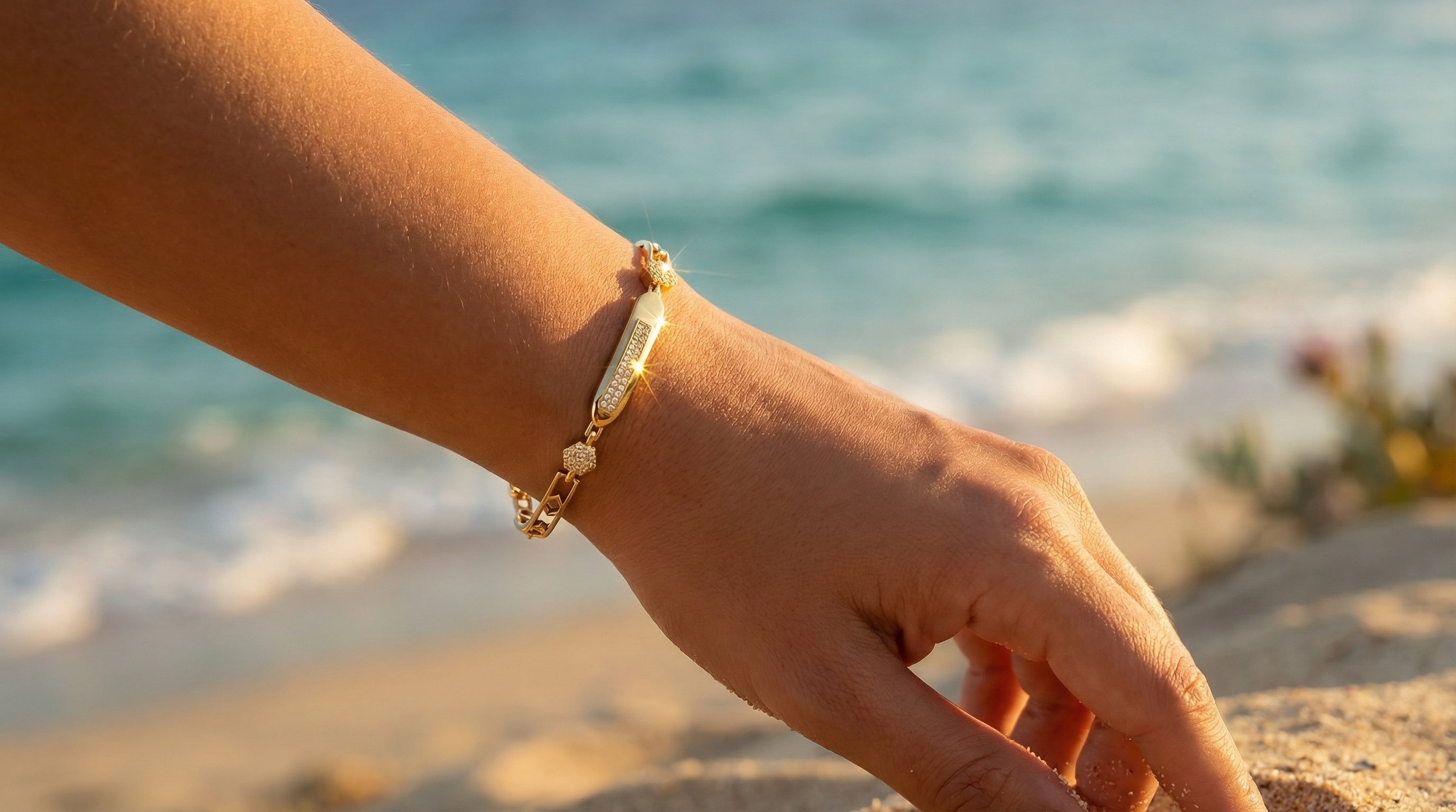 Hand wearing a gold bracelet with a blurred beach background