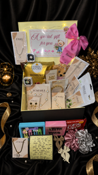 Gift box with various items including jewelry and snacks on a dark background
