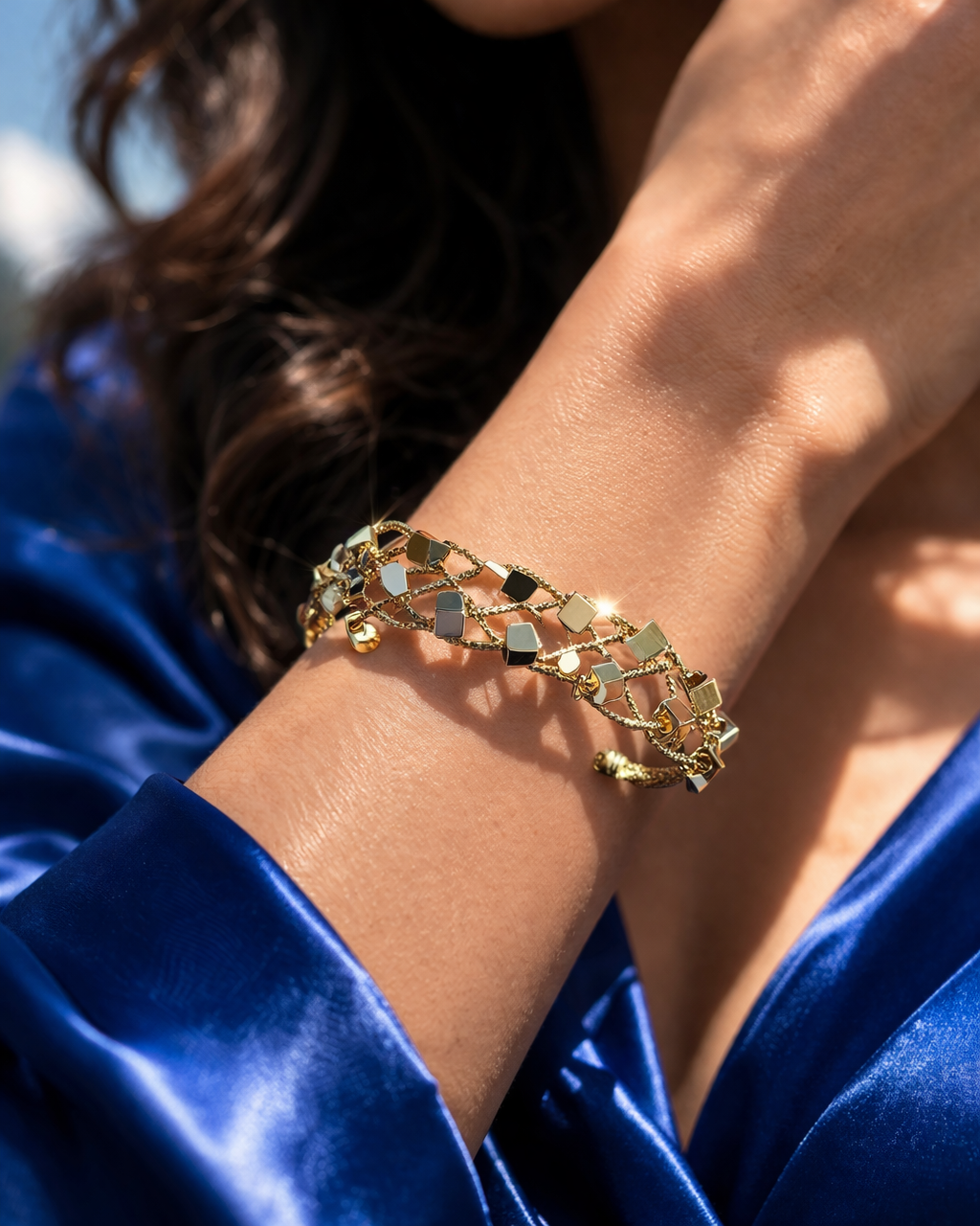 Gold bracelet on a wrist with a blue satin garment
