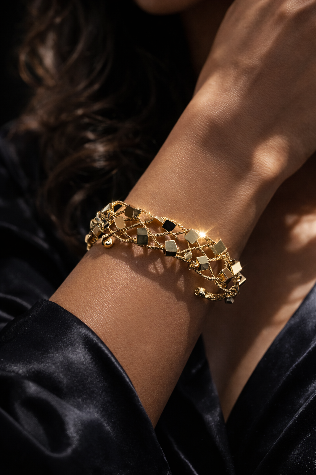 Gold chain bracelet on a wrist with a dark background