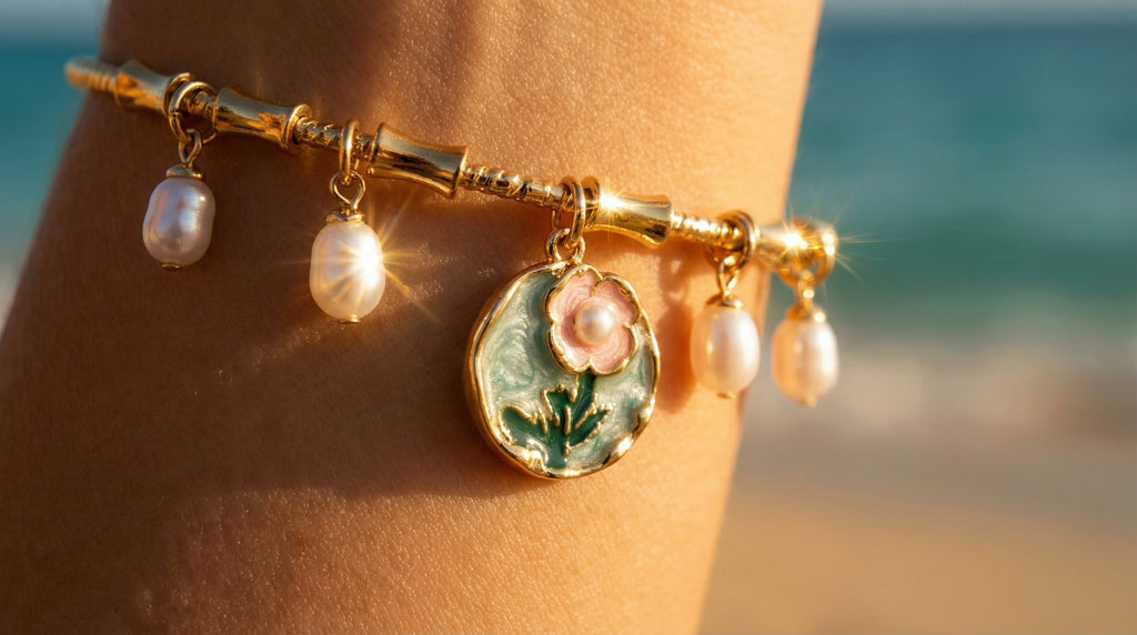 Gold bracelet with charms on a person's wrist against a beach background