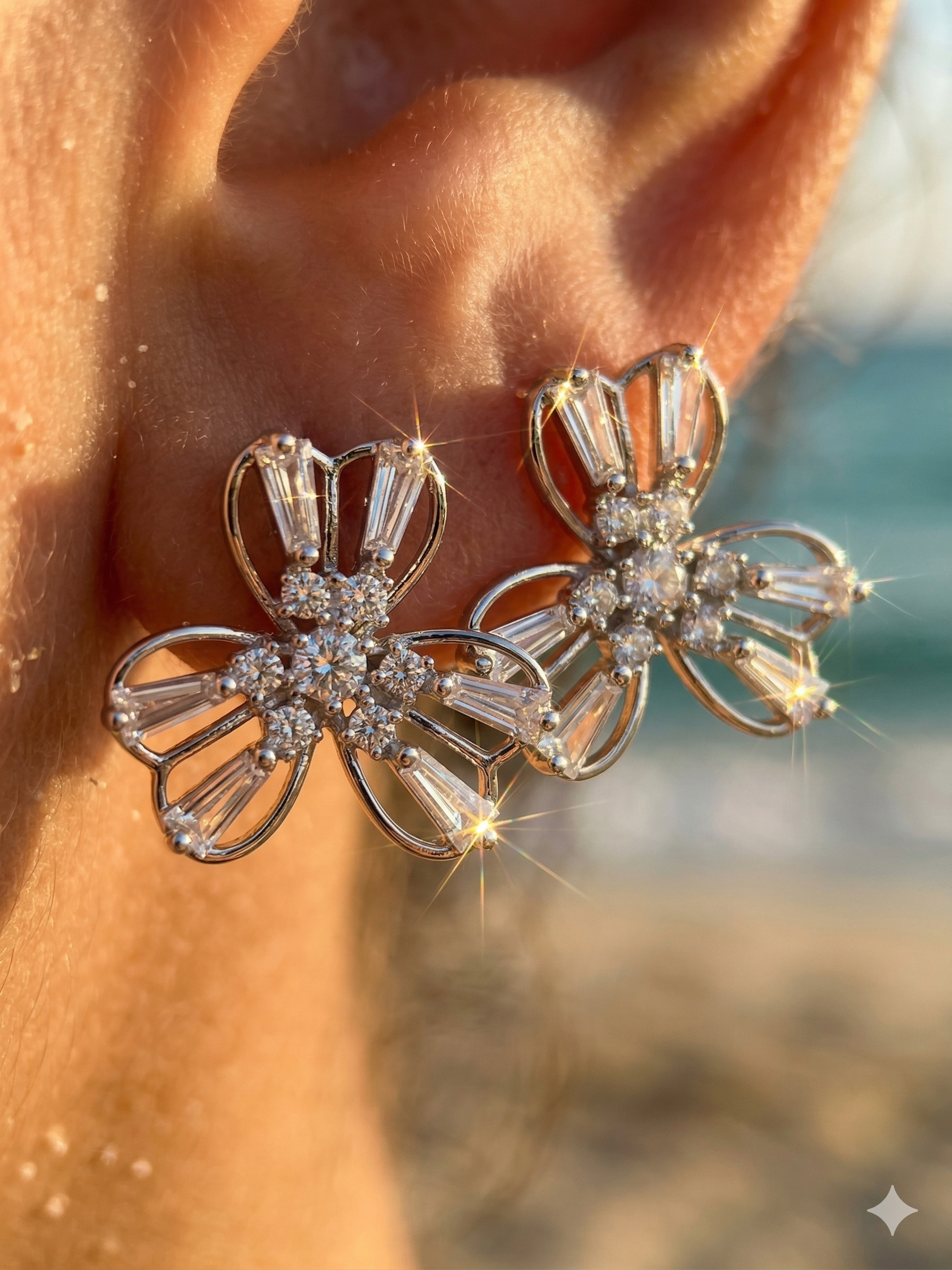 Close-up of a person wearing a pair of ornate earrings with a blurred natural background