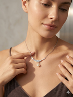 Woman wearing a necklace with a pearl pendant against a neutral background