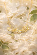 Gold necklace with floral design on a bed of white flowers