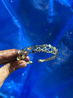 Gold tiara held by a hand against a blue tarp background