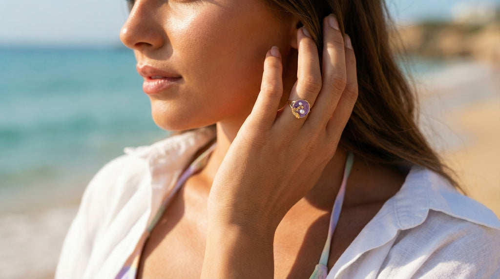 Woman on a beach wearing a ring, with a blurred background of ocean and sand.