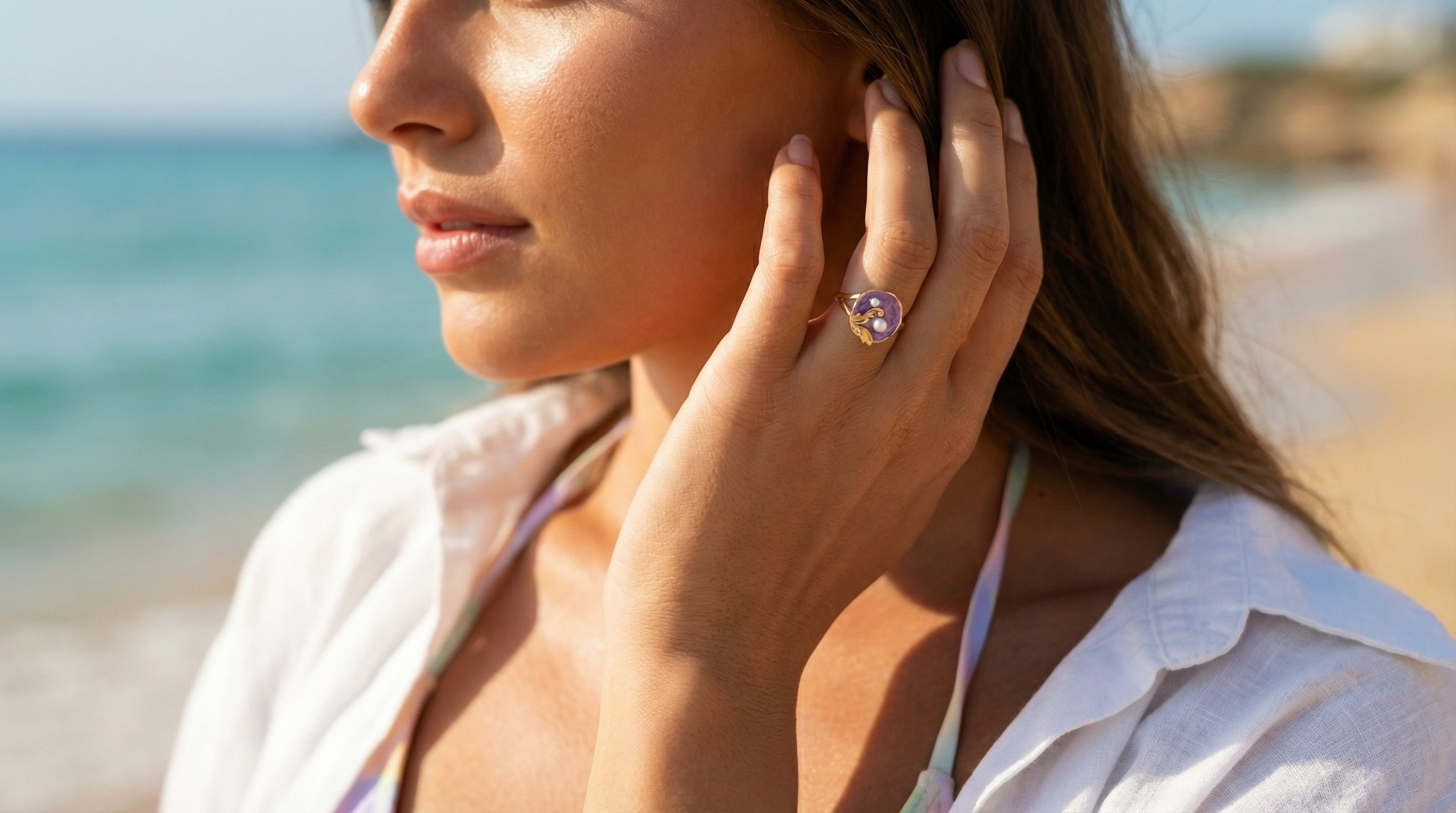 Woman on a beach wearing a ring, with a blurred background of ocean and sand.