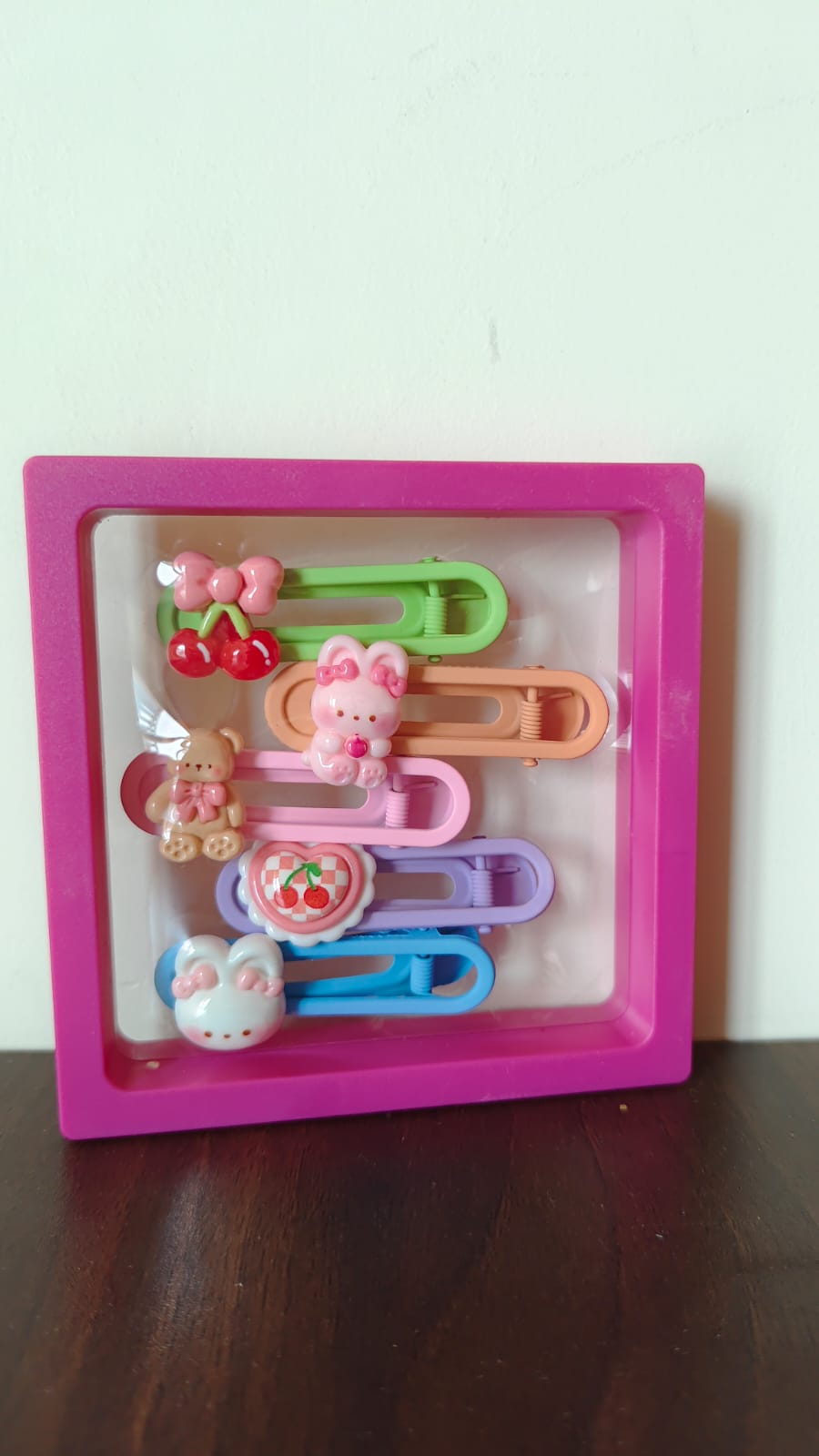 Colorful hair clips in a pink frame with cute decorations like bows and animals. Perfect for styling with hair clips.