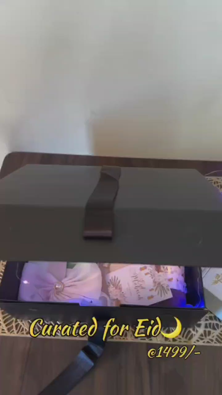 Gift box with jewelry,  Hijab and a Eid card on a decorative mat.