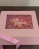 Gift box with various items including a teddy bear, snacks, and beauty products on a dark surface.