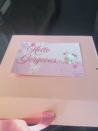 Gift box with anniversary-themed items including a teddy bear, jewelry, and stationery on a dark background.