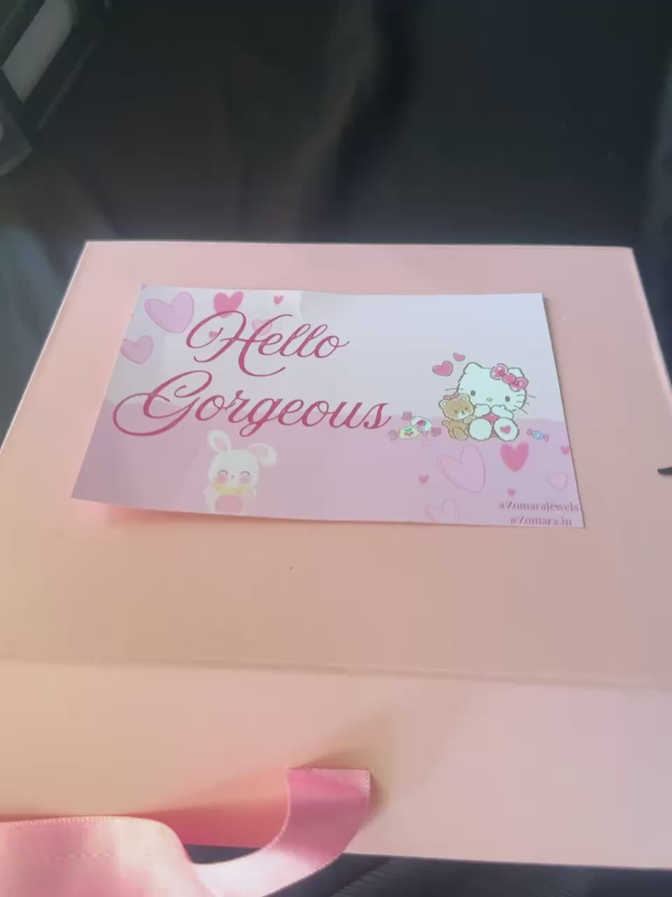 Gift box with anniversary-themed items including a teddy bear, jewelry, and stationery on a dark background.