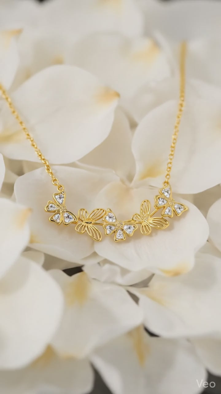 Delicate gold-toned necklace featuring butterfly and flower pendants embellished with sparkling crystals

