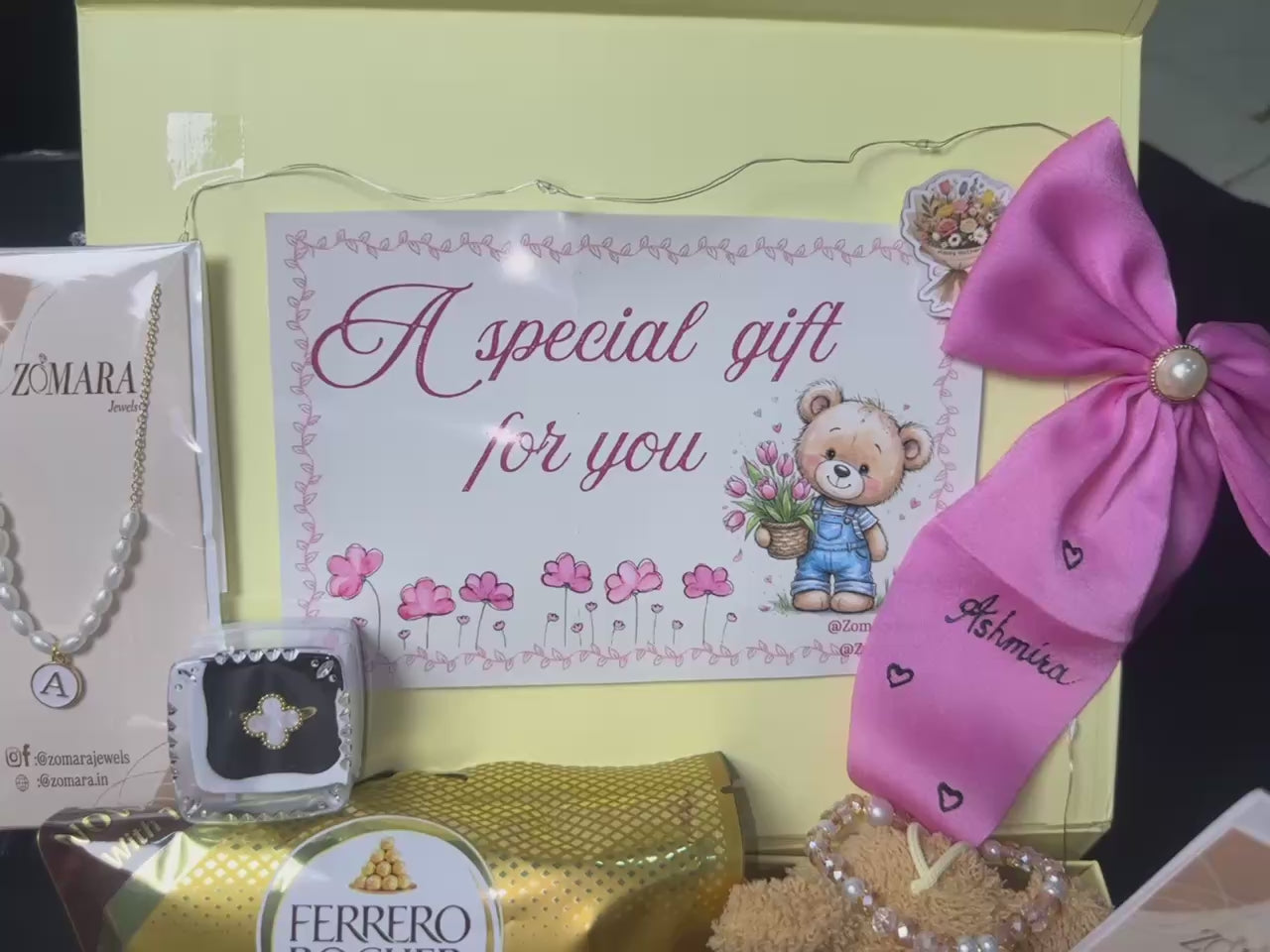 Gift basket with various items including chocolates, jewelry boxes, and decorative bows on a dark background.