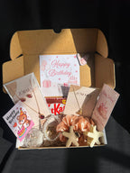 Gift box with birthday cards, KitKat bar, and decorative items on a dark background
