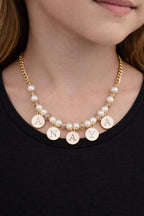 Necklace with pearls and gold lettered pendants on a black background