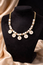 Pearl necklace with 'ANAYA' charms on a black stand with beige fabric background