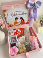 Rakshabandhan gift hamper by ZOMARA with pearl necklace, jhumka earrings, bracelets, hair scrunchies, KitKat chocolate, and Happy Rakshabandhan greeting card in a pink gift box