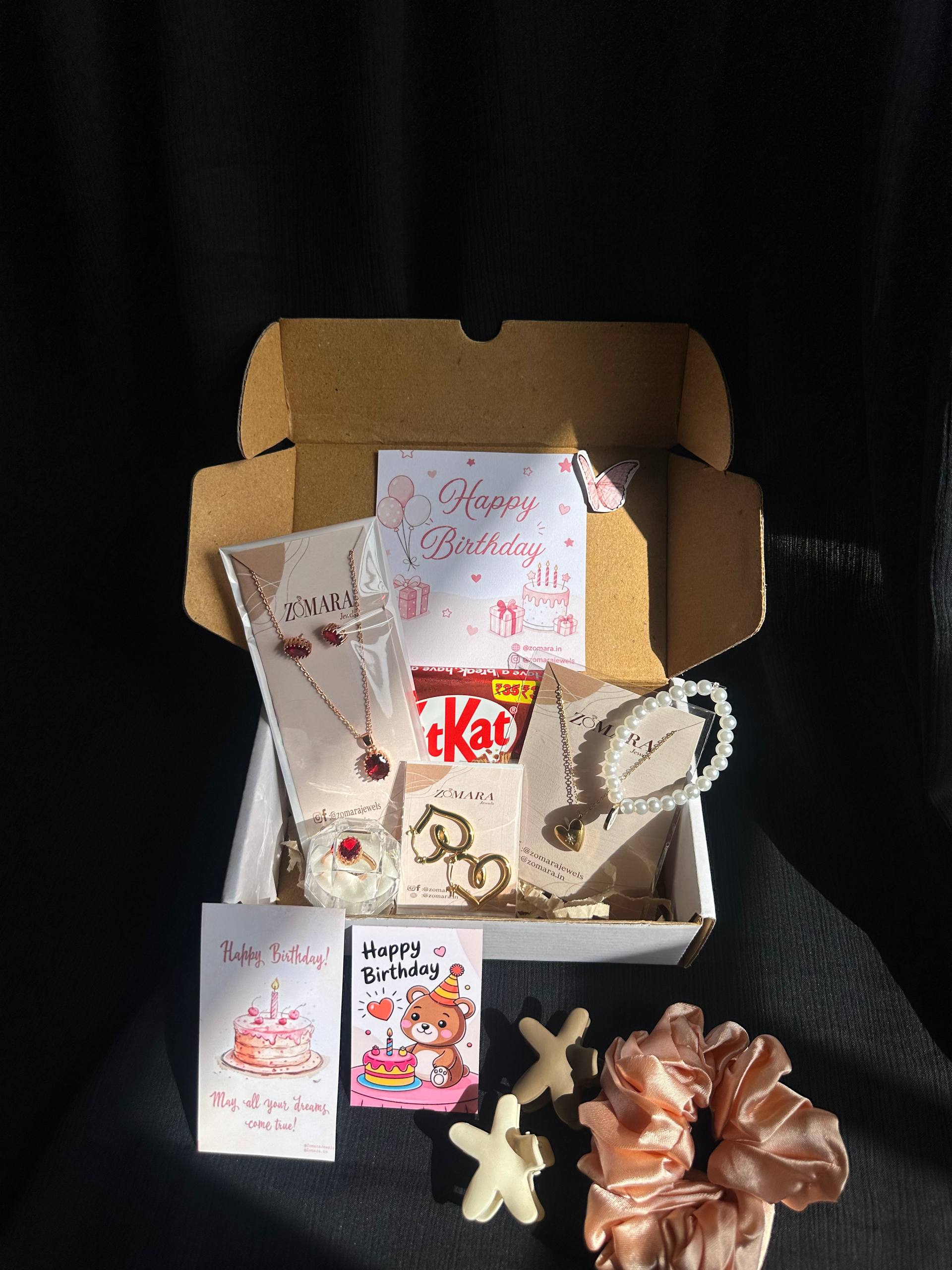 Gift box with jewelry, snacks, and decorative items on a dark background